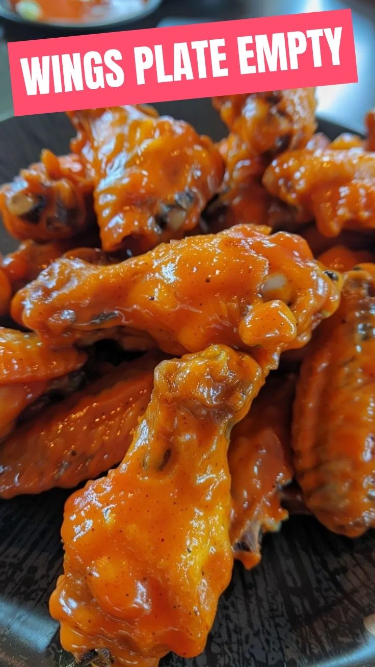 A close-up shot of several buffalo wings coated in a vibrant red sauce, ready to be served.