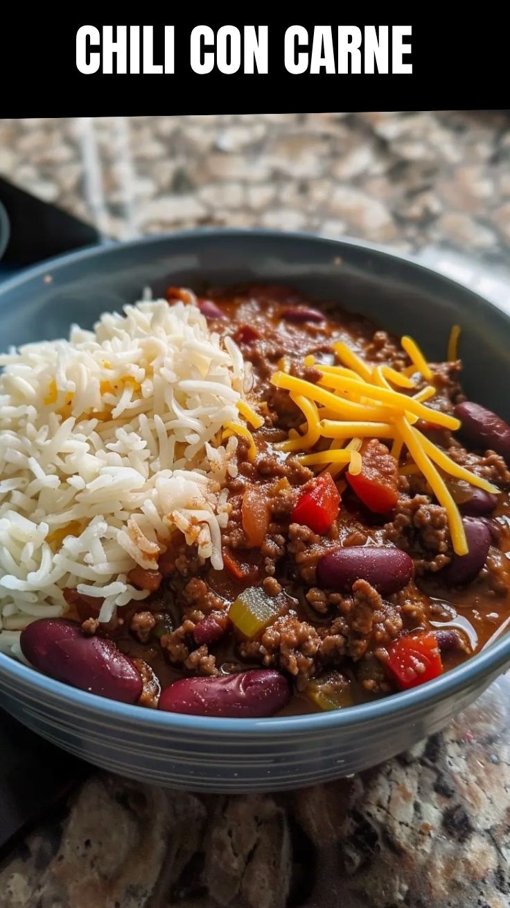 A bowl of rich, red chili con carne garnished with fresh herbs