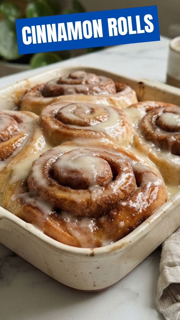 Freshly baked cinnamon rolls in a pan with golden tops and white glaze